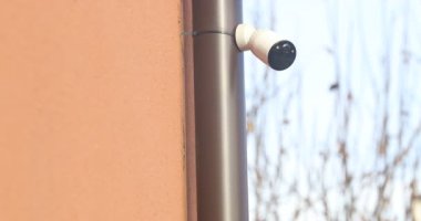 Kırmızı Duvara monte edilmiş Beyaz Kablosuz Güvenlik Kamerasının yakın plan görüntüsü.