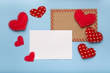 Valentines Day background. Red hearts, paper blank on pastel blue background. Love letter concept, copy space