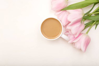 Sabah kahvesi ve pembe çiçekler beyaz masa manzaralı. Düz yatıyordu. Yaratıcı kahvaltı konsepti, üst görünüm, kopyalama alanı