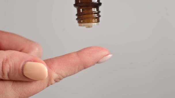 Крупным планом женщина капает масло на палец на белом фоне — стоковое видео