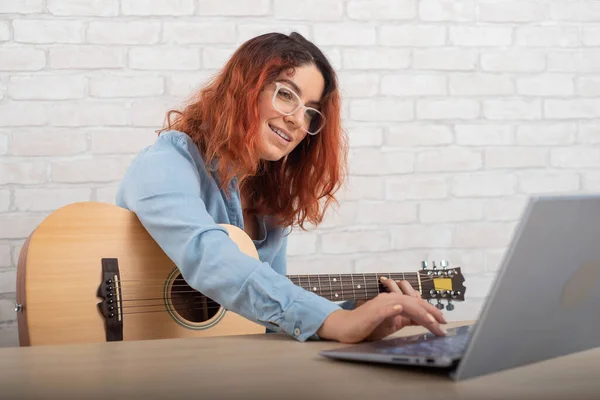 Kaukasische Frau lernt, online Gitarre zu spielen. Das Mädchen sitzt in Quarantäne und studiert Musik — Stockfoto