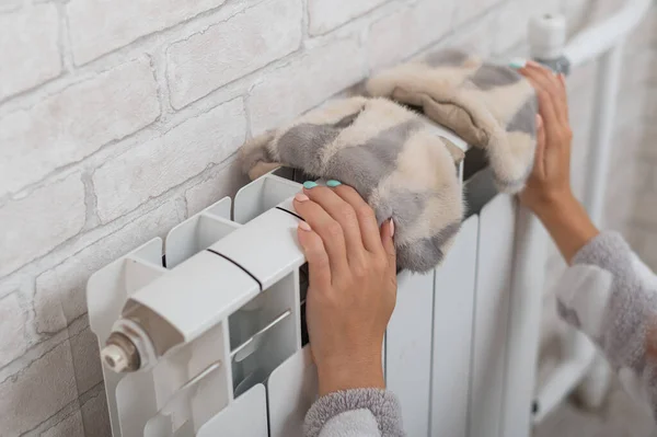 Žena pověsí kožešinové rukavice na chladič. Ústřední topení v chladném zimním dni — Stock fotografie