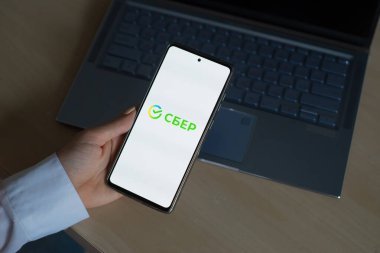 18 Ekim 2020 Rusya, Novosibirsk: Ekranda yeni Sberbank logosu olan bir kadın akıllı telefon tutuyor