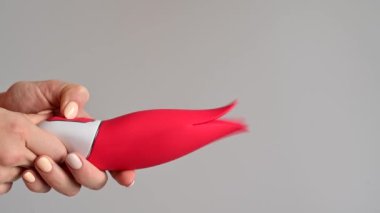 Bir kadın klitoral vibratörü kırmızı lale şeklinde tutuyor. Modern tasarımlı bir seks oyuncağı.