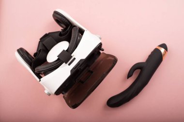 Black dildo and virtual reality helmet on a pink background. Masturbation concept with modern technology