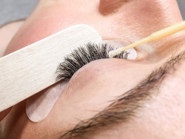 Kirpik uzatma işleminin yakın plan görüntüsü. Güzellik salonunda bir kadının portresi.
