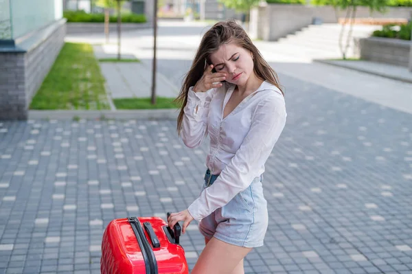 Overstuur meisje met een rode koffer buiten. De vrouw huilt en beweegt als ze uit elkaar gaat. — Stockfoto