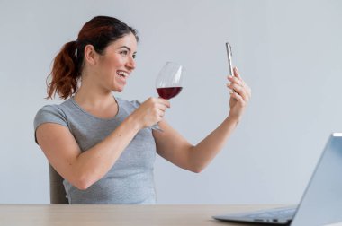 Beyaz bir kadın kırmızı şarap içer ve arkadaşlarıyla akıllı telefondan iletişim kurar. Karantinaya alınan kız, bayramı online bir konferans aracılığıyla kutluyor.