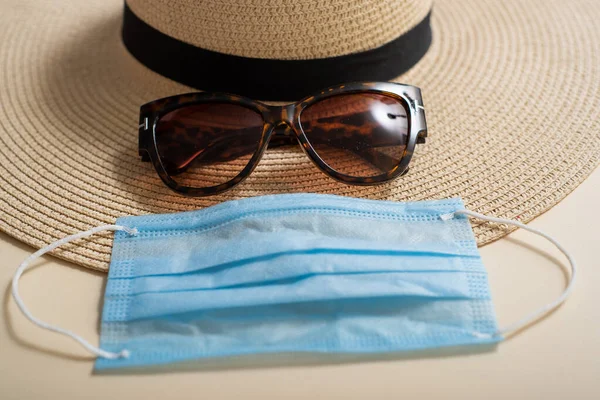 Sunglasses straw hat passport cover and medical mask top view. Vacation concept during the coronavirus epidemic