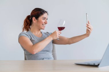 Beyaz bir kadın kırmızı şarap içer ve arkadaşlarıyla akıllı telefondan iletişim kurar. Karantinaya alınan kız, bayramı online bir konferans aracılığıyla kutluyor.