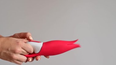 Bir kadın klitoral vibratörü kırmızı lale şeklinde tutuyor. Modern tasarımlı bir seks oyuncağı.