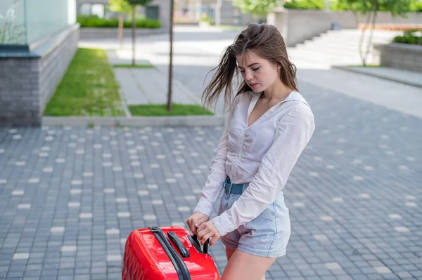 Aufgebrachtes Mädchen mit rotem Koffer im Freien. Die Frau weint und bewegt sich, als sie auseinanderbricht — Stockfoto