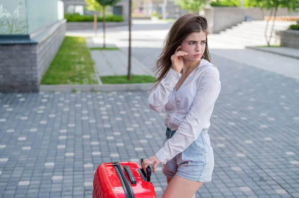 Overstuur meisje met een rode koffer buiten. De vrouw huilt en beweegt als ze uit elkaar gaat. — Stockfoto