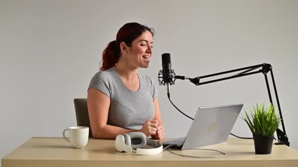 Een charmante vrouw radio host zendt live uit op een laptop. Onlineradioconcept — Stockvideo