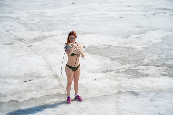 Une femme en bikini se promène avec un chien dans la neige — Photo