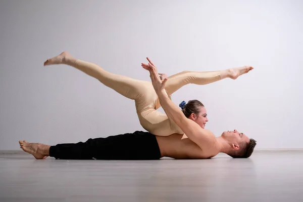 Un dúo de acróbatas mostrando un truco de pareja. Una mujer en un mono de gimnasia con un pie de mano sobre un hombre sin camisa se acuesta boca arriba. Artistas de circo muy flexibles. — Foto de Stock