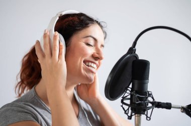 Kulaklıklı bir kadın kayıt stüdyosunda şarkı kaydediyor. Duygusal kız zevkle şarkı söyler