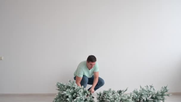 Мужчина делает и украшает искусственную елку — стоковое видео