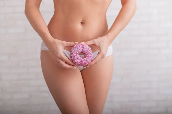 하얀 팬티를 입은 얼굴없는 여자가 분홍색 도넛을 들고 있다 — 스톡 사진