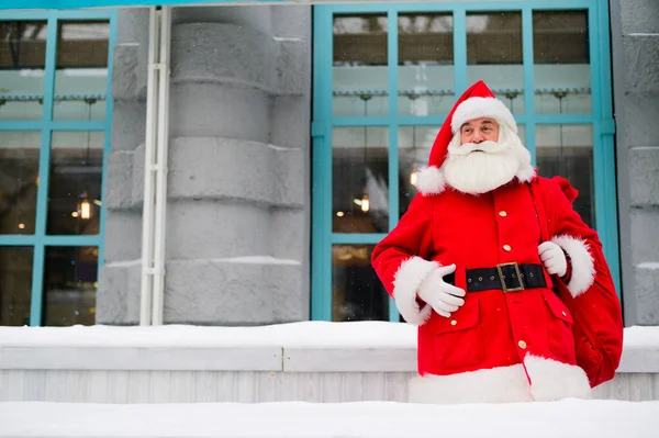 Тщательный Санта Клаус зимой прислоняется к фасаду дома — стоковое фото
