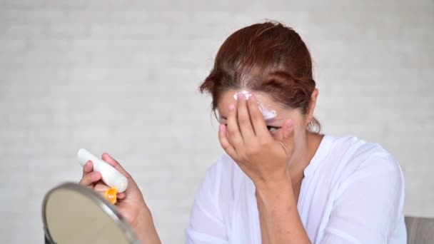 Портрет кавказької жінки з дисеями вітиліго використовує сонцезахисний крем. — стокове відео