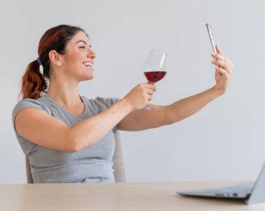 Beyaz bir kadın kırmızı şarap içer ve arkadaşlarıyla akıllı telefondan iletişim kurar. Karantinaya alınan kız, bayramı online bir konferans aracılığıyla kutluyor.