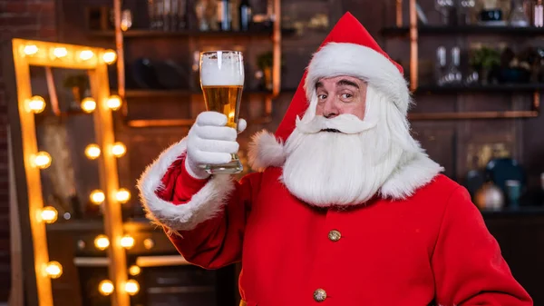 Santa Claus pije pivo, zatímco sedí v koženém křesle — Stock fotografie