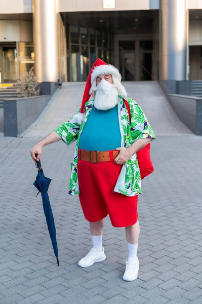 Portrait de Père Noël claus en masque de protection chemise hawaïenne et short à l'extérieur. Noël dans le coronavirus — Photo