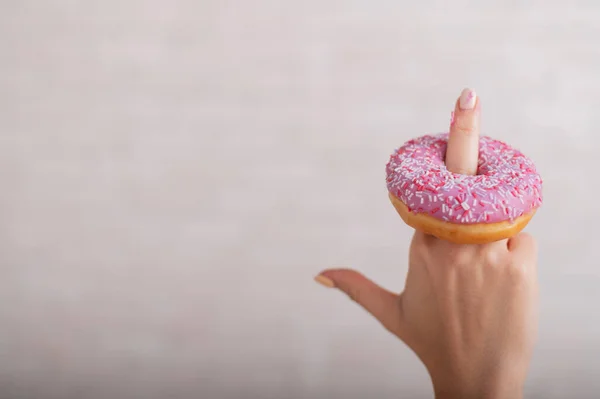 Donut on the female middle finger. Sex gesture — Stock Photo, Image