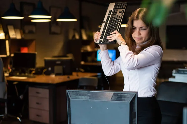 Нервный срыв на работе. Деловая женщина выходит из себя и ломает компьютер в офисе — стоковое фото