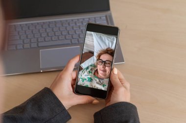 İş kadını akıllı telefondan yaşlı hasta bir anneye video araması yapıyor.