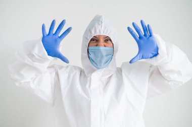 Koruyucu giysili bir kadın ve korkunç bir buruşukluğu olan tıbbi bir maske. Doktor avuçlarını yüzüne dayadı ve korktu.