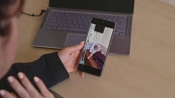 Zakelijke vrouw maakt een video-oproep op een smartphone naar een zieke oudere moeder in een ziekenhuis — Stockvideo