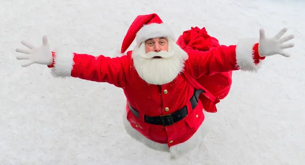 Vista superior en Santa Claus amistoso activamente gesto y deseando feliz Navidad. Un anciano disfrazado de Papá Noel está parado en la nieve afuera y desea un feliz año nuevo.. — Foto de Stock