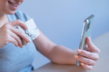 Mutlu kadın blogcu telefonda bir hediye gösteriyor.