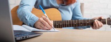 A woman with a guitar writes notes in a notebook. The girl composes a song clipart