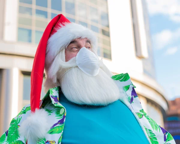 Portræt af julemanden claus i beskyttende maske hawaiian skjorte udendørs. Jul i coronavirus - Stock-foto