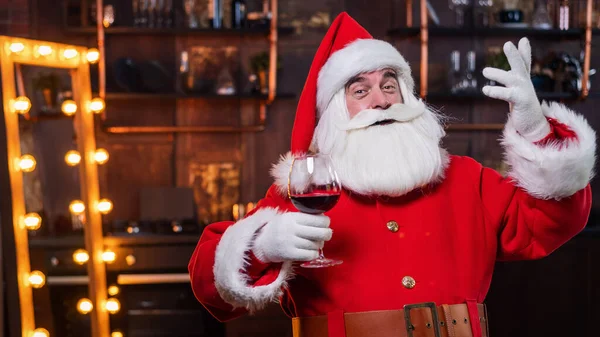 Santa Claus con una copa de vino tinto desea feliz Navidad y dice brindis —  Fotos de Stock