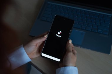18 Ekim 2020 Rusya Novosibirsk: Ekranda tik tok logosu olan bir kadın telefonu tutuyor. Kız komik videoları olan mobil bir uygulama izliyor.