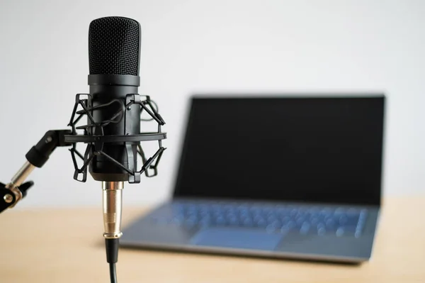 Närbild av en professionell mikrofon på bakgrunden av en bärbar dator. Skrivbord för radioföretag — Stockfoto