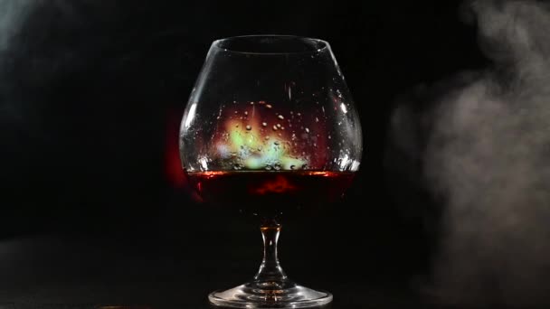 Ένα ποτήρι κονιάκ στο φόντο του τζακιού και του καπνού των πούρων. — Αρχείο Βίντεο