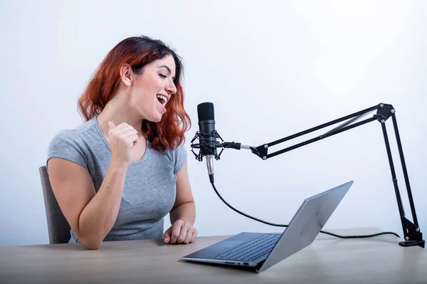 Egy érzelmes nő sugároz a neten egy laptopon. Női rádiós műsorvezető a munkahelyen — Stock Fotó