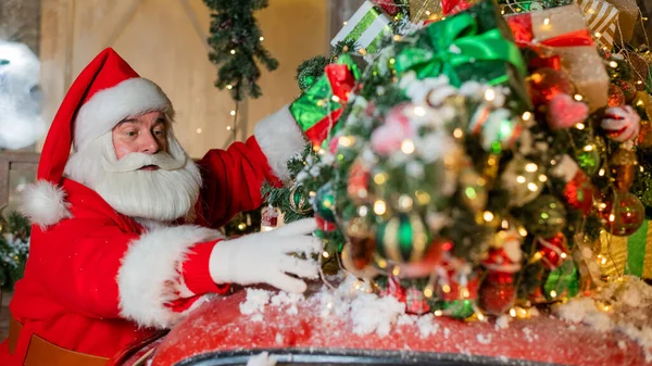 Papai Noel anexa a árvore de Natal e presentes para o clássico carro vermelho. Tempo de Natal. — Fotografia de Stock