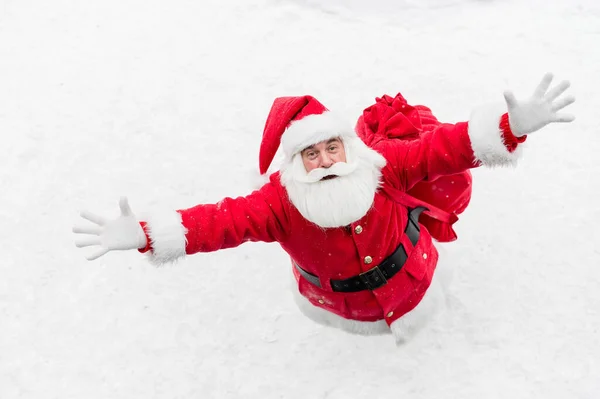 Vue de dessus sur le père noël amical claus activement geste et souhaiter joyeux Noël. Un vieil homme en costume de Père Noël se tient sur la neige dehors et souhaite une bonne année. — Photo
