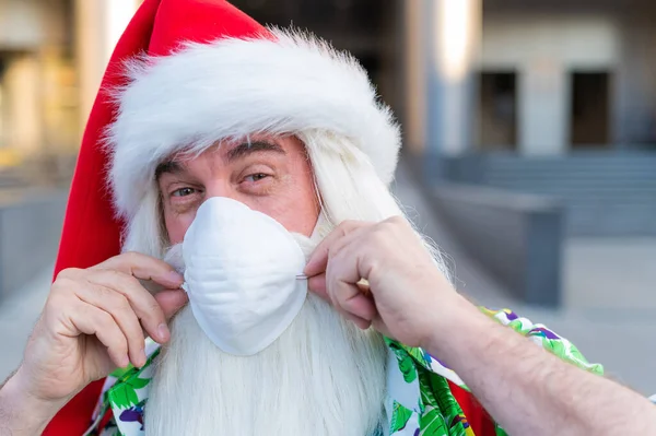 Portret van de kerstman in beschermende masker Hawaï shirt buiten. Kerstmis in het coronavirus — Stockfoto