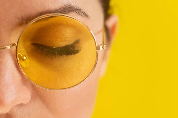 Retrato de cerca de una mujer con gafas de sol sobre un fondo amarillo —  Fotos de Stock