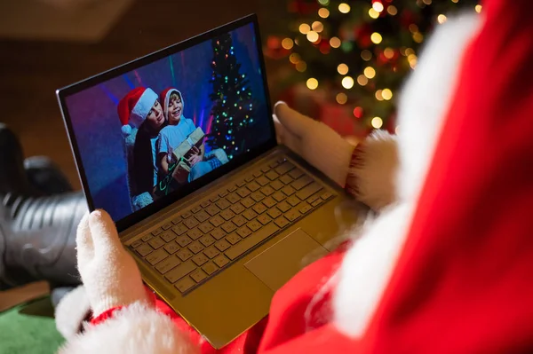 Mãe e filho felizes conversando com o Papai Noel por vídeo chat em um laptop. Mulher e menino deseja remotamente Feliz Natal — Fotografia de Stock