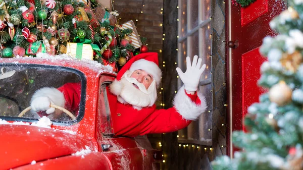 Санта Клаус здоровается за рулём красной ретро-машины. Счастливого Рождества! — стоковое фото