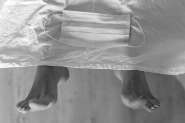 Morgda maskeli ölü bir kadının ayakları. Koronavirüs salgınının kurbanı..