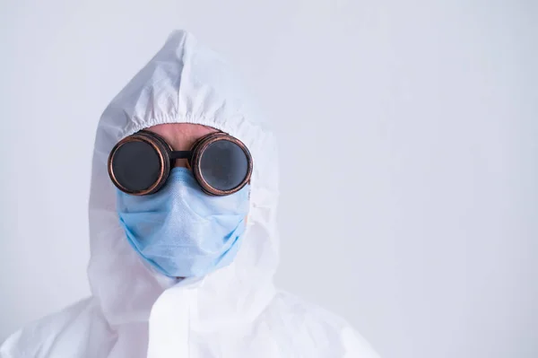 Retrato de una mujer en traje de protección con una máscara con gafas sobre fondo blanco. Una doctora de uniforme durante una pandemia. — Foto de Stock